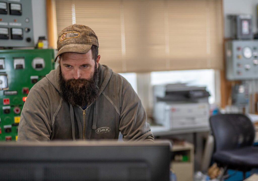 Man working on a computer at a company named Gray & Son a leading site and development contractor in Maryland.