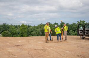 Five construction workers in a dirt field, one female three male, working together for Gray & Son a leading site and development contractor in Maryland.