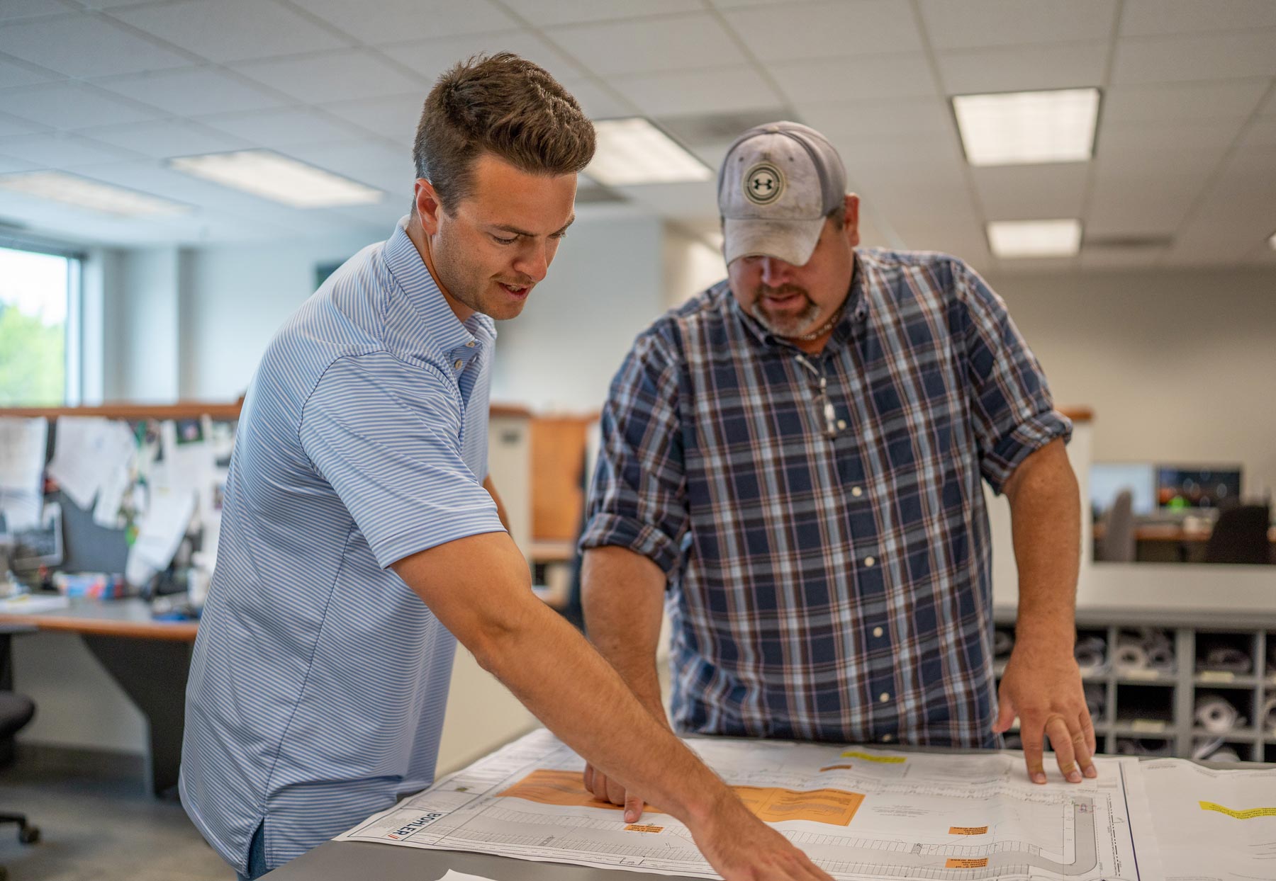Two male workers reviewing a blueprint who work for a company named Gray & Son a leading site and development contractor in Maryland.
