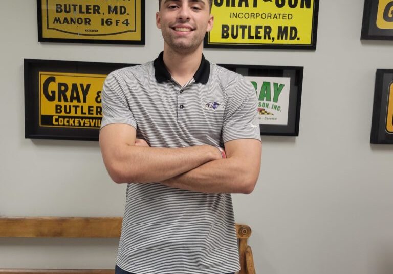 A full length photo of a man standing and smiling at the camera in an office who works for a company named Gray & Son a leading site and development contractor in Maryland.