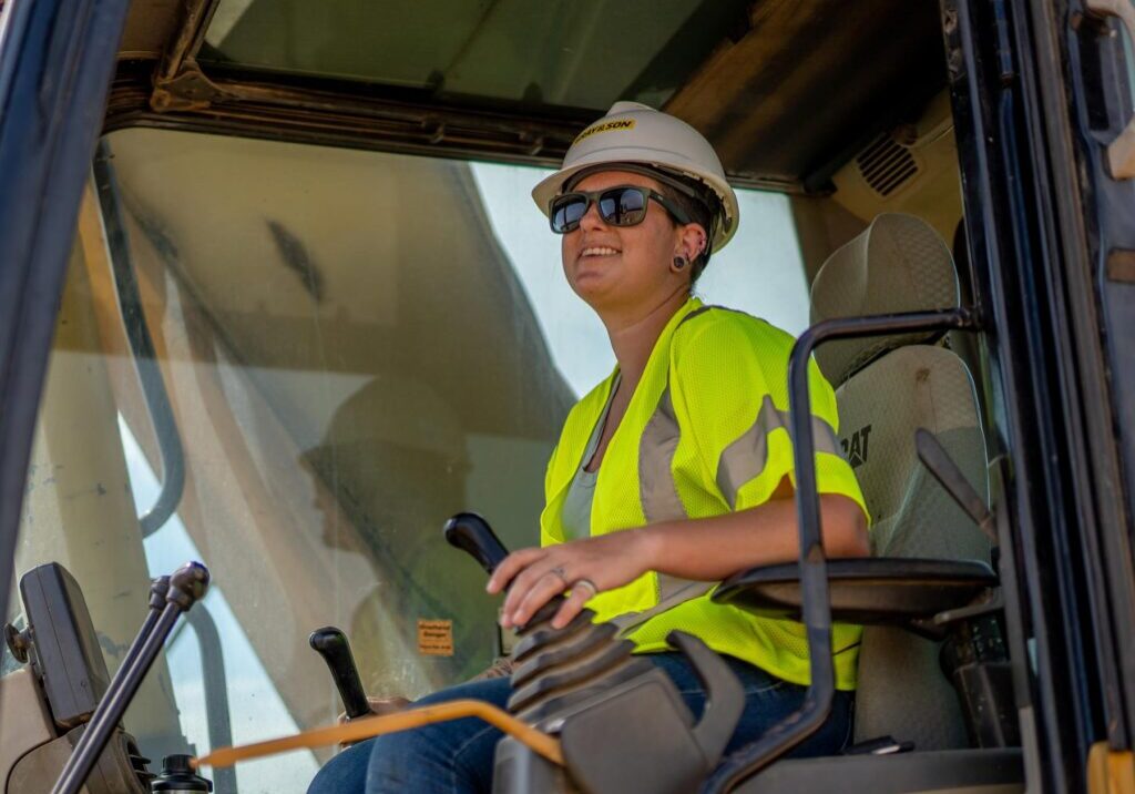 Female worker operating a construction crane smiling and working for Gray & Son a leading site and development contractor in Maryland.