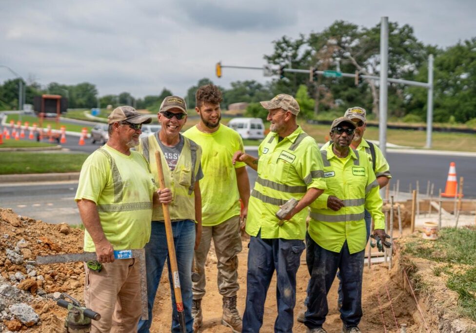 six male construction workers smiling and talking together who work for Gray & Son a leading site and development contractor in Maryland.