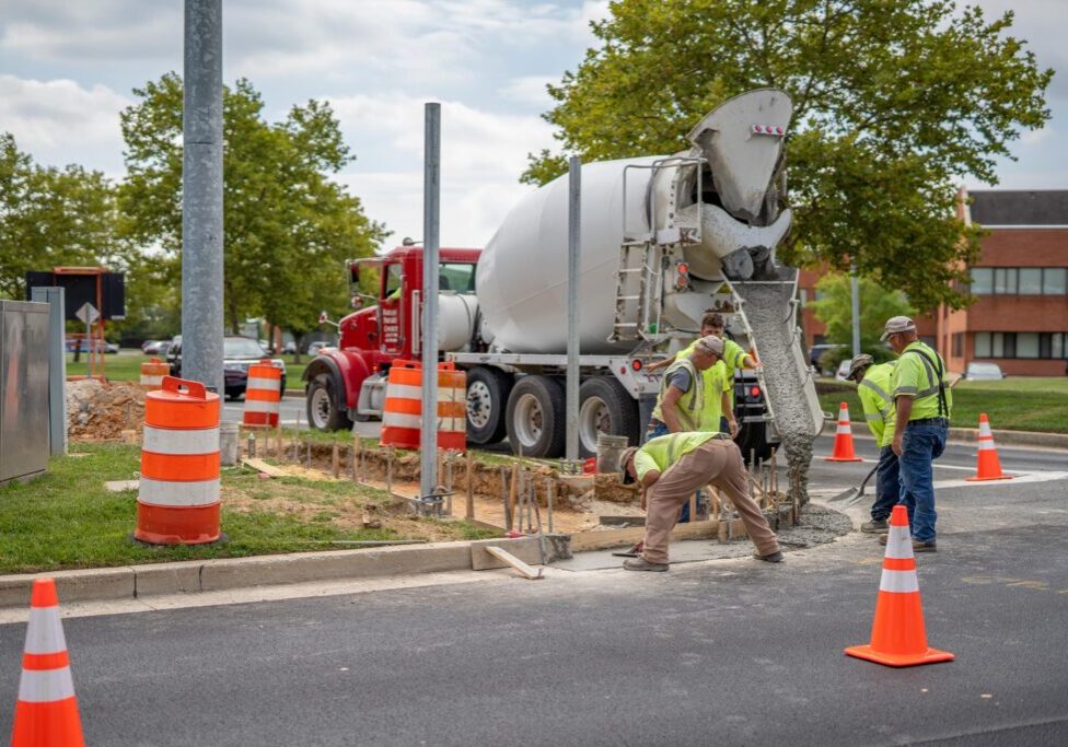 Three construction workers building a side walk operating a concrete mixer truck, they work for Gray & Son a leading site and development contractor in Maryland.